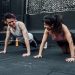 Man and woman doing pushups while smiling during a workout inside a Mexico City gym.